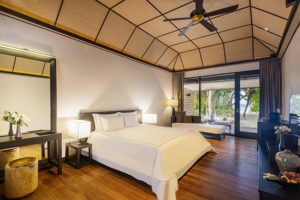 Hotelzimmer Beach Villa mit Doppelbett, Holzboden, großen Fenstern und Blick auf Terrasse und Strand