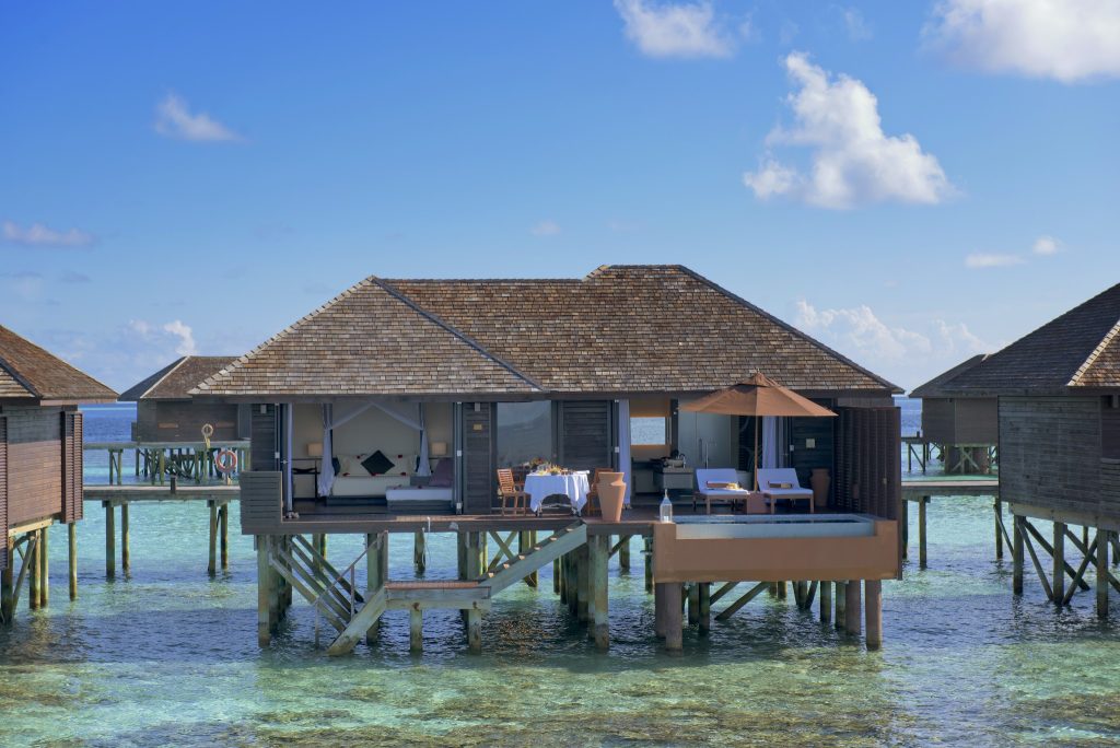 Über dem Wasser gebautes Deluxe Water Villa Zimmer mit Holzterrasse und Dach aus Holzschindeln im Lily Beach Resort & Spa