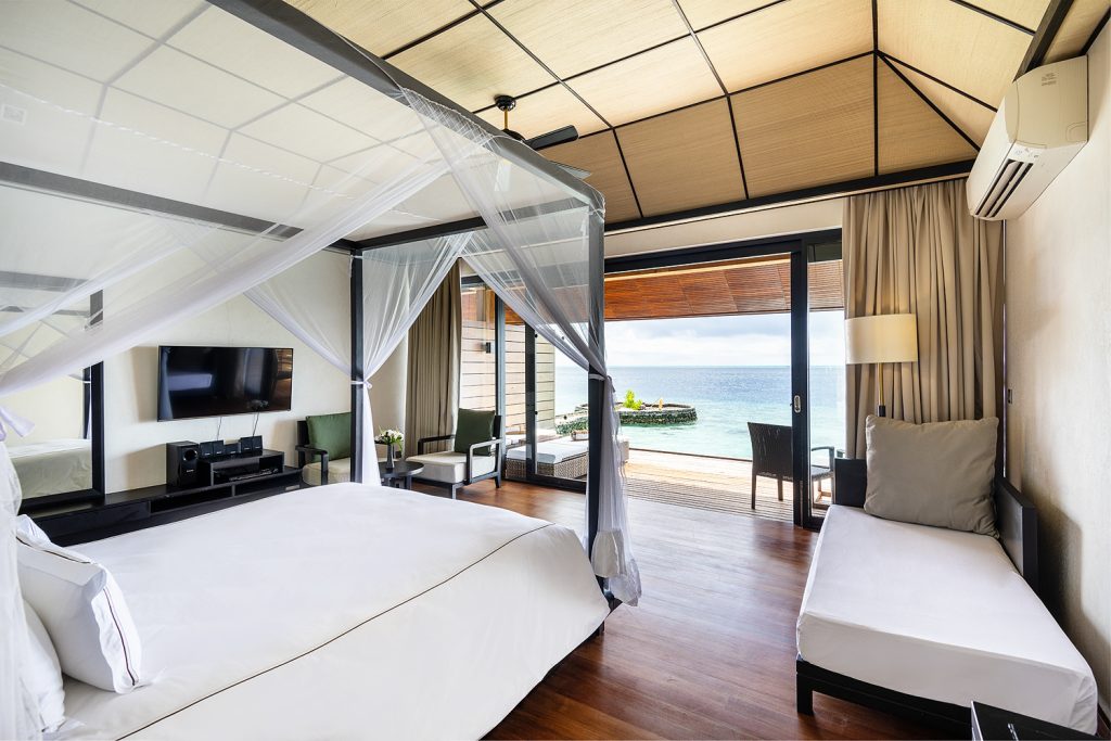 Zimmer der Lagoon Villa im Lily Beach Resort & Spa mit Himmelbett, Holzboden, Terrasse und Meerblick