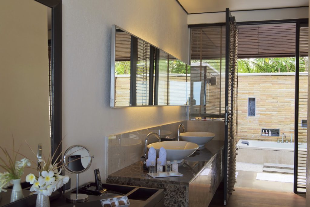 Badezimmer mit zwei runden Waschbecken, Marmorablage, großem Spiegel und Blick auf Außenbereich im Lily Beach Resort & Spa