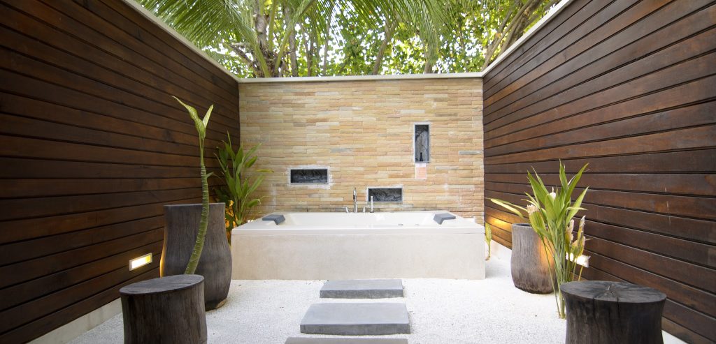 Offener Außenbereich der Lagoon Villa mit freistehender Badewanne, dunklen Holzwänden