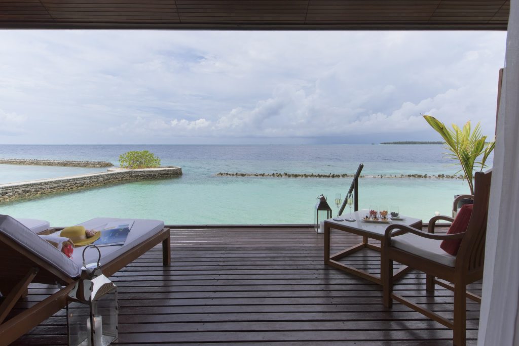 Terrasse der Lagoon Villa im Lily Beach Resort & Spa mit zwei Holzliegestühlen und Blick auf türkisfarbenes Meer