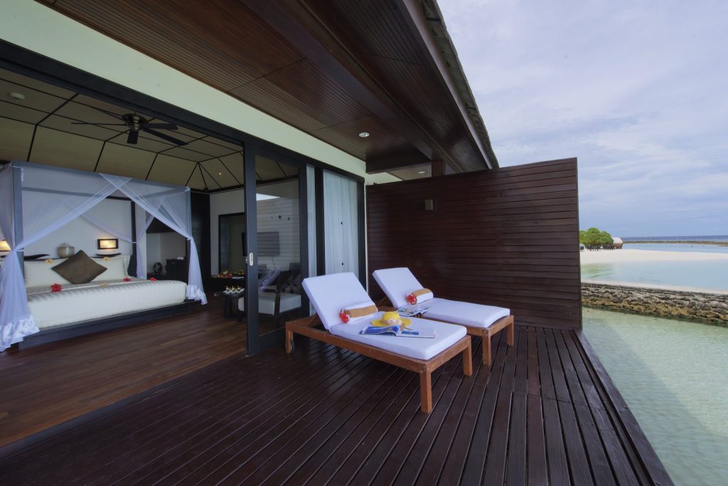 Terrasse der Lagoon Villa mit weißen Liegestühlen und Blick auf Wasser, Schlafzimmer mit Moskitonetzbett und Holzausstattung
