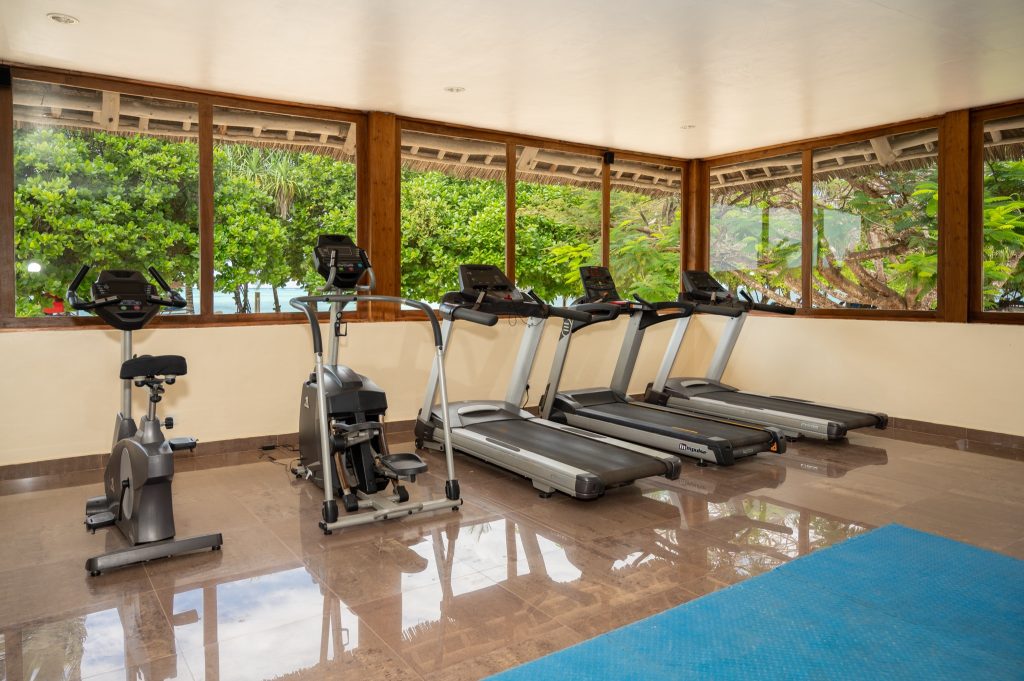 Fitnessraum im Neptune Pwani Beach Resort & Spa mit Laufbändern, Stepper, Heimtrainer und großen Fenstern