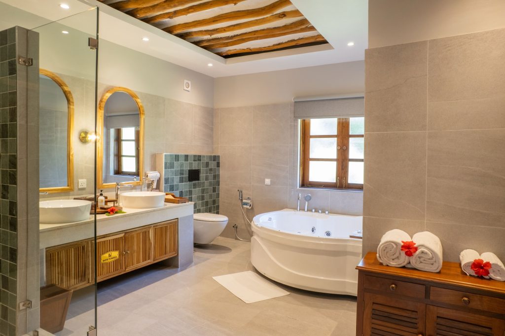 Badezimmer im Neptune Pwani Beach Resort & Spa deluxe-garden-room mit Eckbadewanne, Waschtischkonsole und Holzbalkendecke