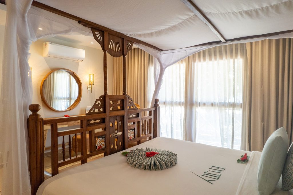 Deluxe Room im Neptune Pwani Beach Resort & Spa mit Himmelbett aus geschnitztem Holz und Tageslicht