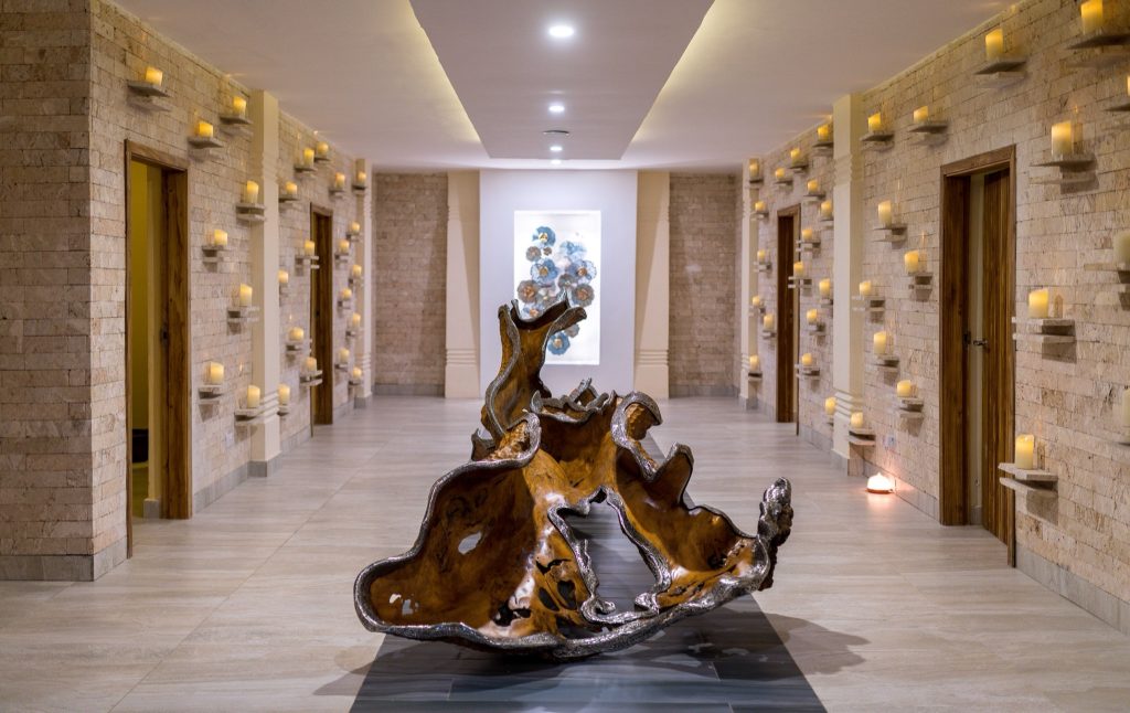 Hotelflur im Royal Zanzibar Beach Resort mit hellbeigen Steinwänden, Kerzen, Holzskulptur und blau-goldenem Kunstwerk
