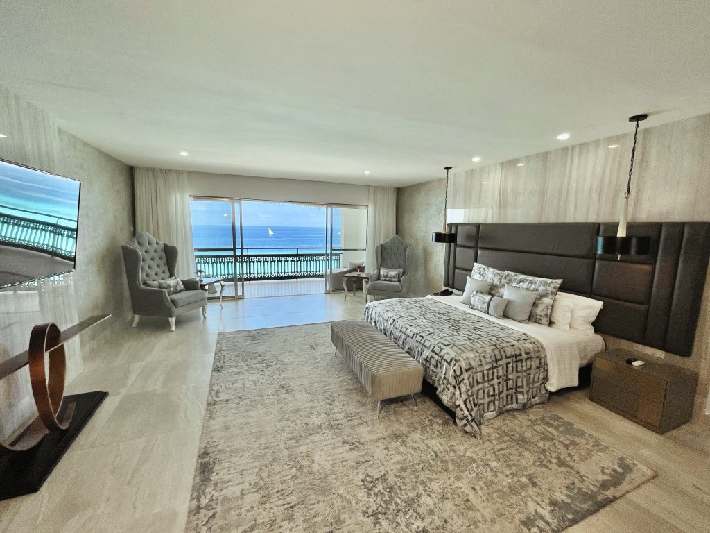 Geräumiges Hotelzimmer Royal Suite mit großem Bett, zwei Sesseln, Holznachttisch und Meerblick in Sansibar