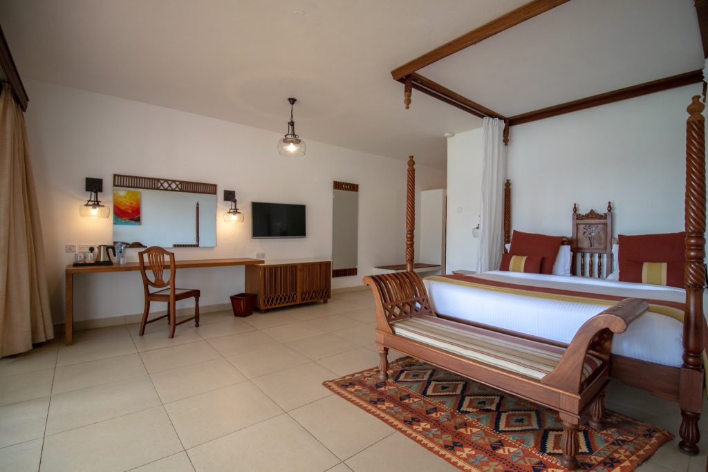 Geräumiges Superior Room im Royal Zanzibar Beach Resort mit Himmelbett, Holzmöbeln, Flatscreen-TV und beige Fliesen