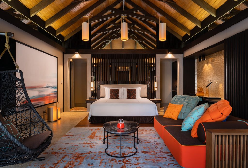 Hotelzimmer der Beach Pool Villa mit großem Bett, Holzdecke, Hängesessel und schwarz-orangenen Kissen