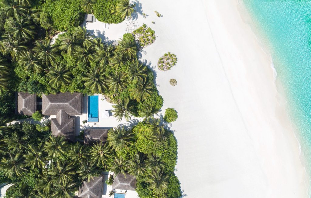 Luftaufnahme der Velaa Private Island deluxe beach pool villa mit Strohdachbungalows, Pool und tropischer Vegetation
