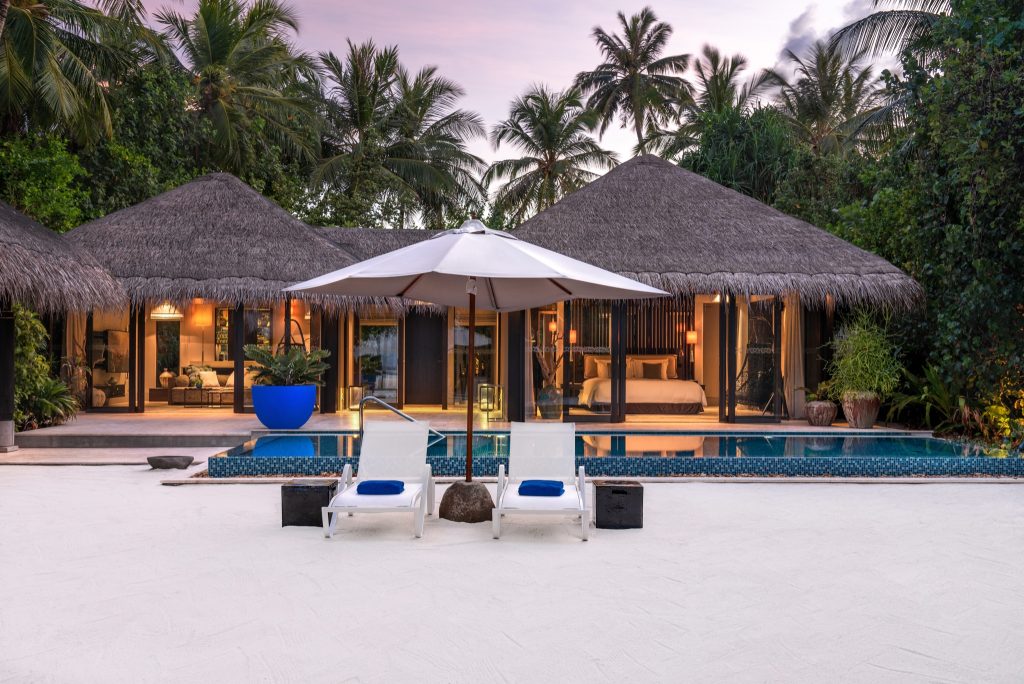 Deluxe Beach Pool Villa mit privatem Pool, zwei Liegestühlen, Sonnenschirm und gläsernen Schiebetüren auf Velaa Private.