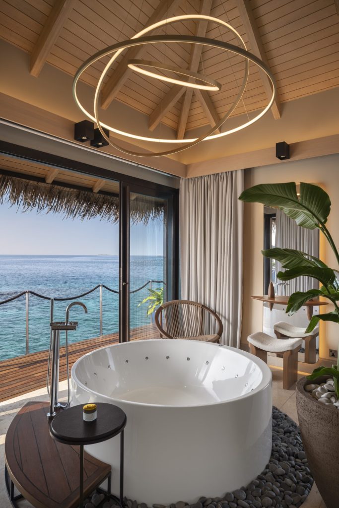 Badezimmer im Ocean Pool House mit freistehender Badewanne, Holzdekor und großer Glasschiebetür zum Meer auf den