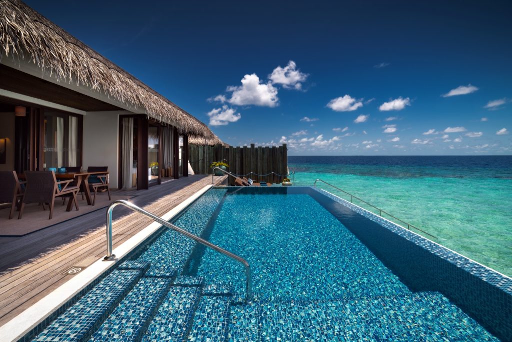 Außenansicht der Sunrise Water Pool Villa mit privatem Pool, Holzterrasse und Strohdach am Meer auf den