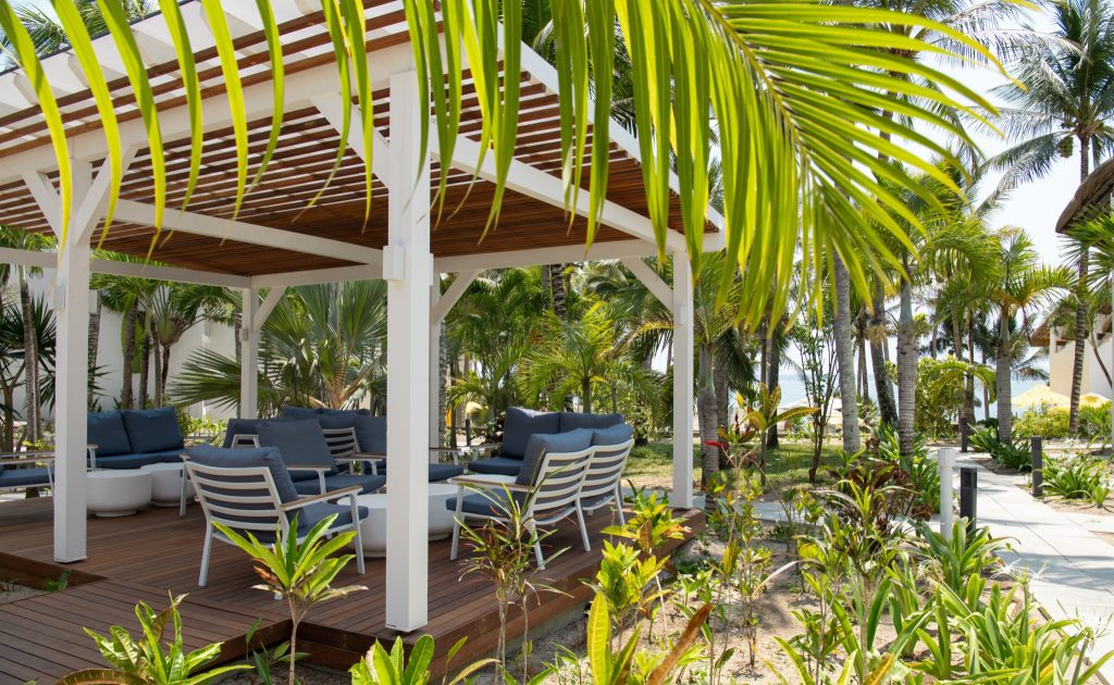 Überdachte Terrasse mit weißem Holzgerüst und blauen Sitzkissen im Veranda Palmar Bar Main Bar auf Mauritius