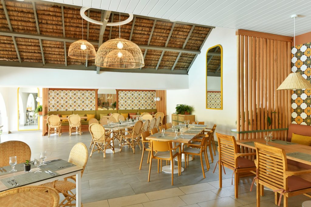 Restaurant Regatta mit hölzernen Tischen, Stühlen, Rattangelampen und Holzlamellen-Trennvorhang im Veranda Palmar Beach Hotel
