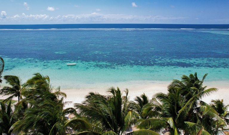 Strand vor türkisfarbenem Meer mit hohen Palmen und weißem Sand im Veranda Palmar Beach Hotel auf Mauritius