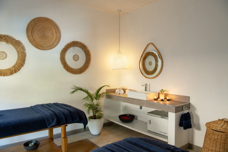 Wellnessraum im Veranda Palmar Beach Hotel mit zwei Massageliegen, Steinwaschtisch, hängendem Spiegel und Naturdekoration
