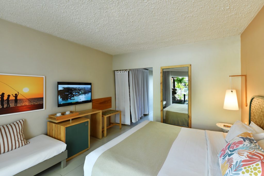 Comfort Garden Zimmer mit Bett, Sofa, Kommode, Flachbildfernseher und Blick auf Palmen in Mauritius