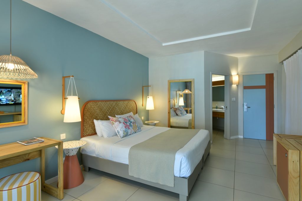 Modernes Hotelzimmer mit Doppelbett, blau gestrichener Wand und hölzernem Schreibtisch im Veranda Palmar Beach Hotel