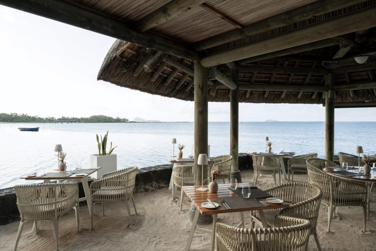 Restaurantterrasse Le Saint Géran mit geflochtenen Tischen und Stühlen auf Sandboden unter Strohdach am Wasser in Mauritius