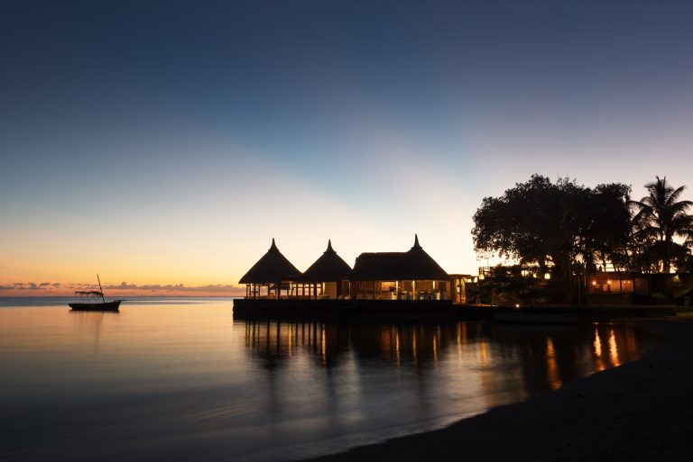 Restaurant Le Saint Geran mit Strohdächern und Holzbau direkt am Wasser bei Sonnenuntergang in Mauritius