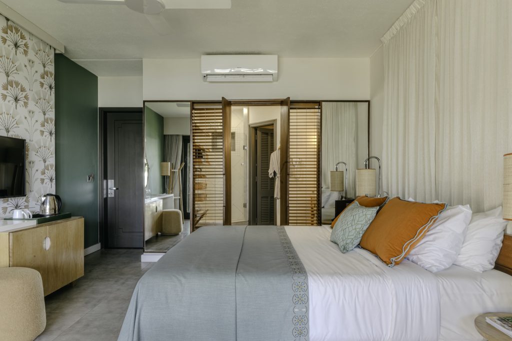 Hotelzimmer Superior Room mit großem Bett, weißen und türkisfarbenen Bettlaken, orangen Kissen und floraler Tapete