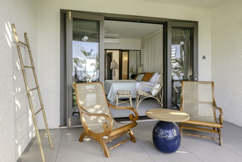 Terrasse des Superior Room im Veranda Paul et Virginie mit Rattan-Sesseln, blauem Tisch und Blick ins Zimmer