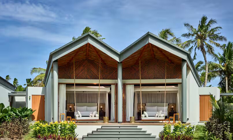 Moderne Hotelvilla mit zwei großen geöffneten Fenstern und überdachtem Sitzbereich mit Sofas