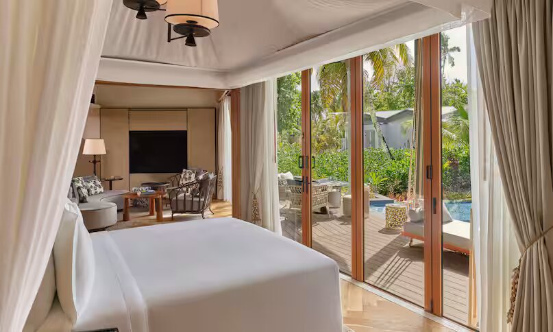 Hotelzimmer Grand Hawksbill Pool Villa mit großem Bett, weißen Vorhängen, Holzschiebetüren und privater Terrasse auf den.