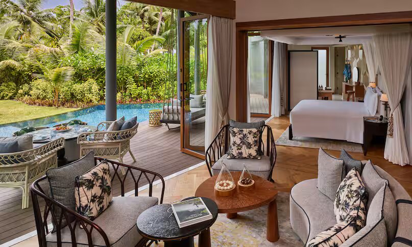 Terrasse der Hawksbill Garden Pool Villa mit Sitzmöbeln, Holzboden, Pool und üppiger Vegetation auf den