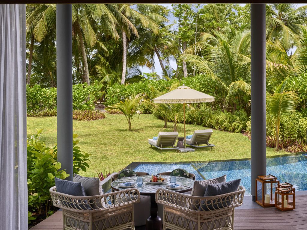 Terrasse der Hawksbill Pool Villa mit Tisch, zwei Rattansesseln, Pool und tropischem Garten auf den