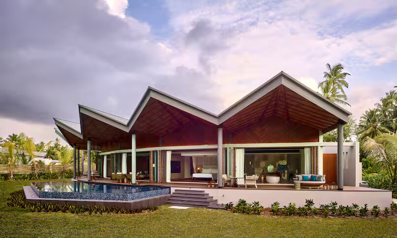 Moderne Kingfish Pool Villa mit gezacktem Dach, Infinity-Pool und großen Glasflächen im Waldorf Astoria Seychelles Platte.