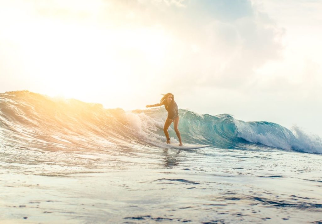 Surfer reitet eine kraftvolle Welle im offenen Meer bei Sonnenauf- oder -untergang mit goldenem Licht