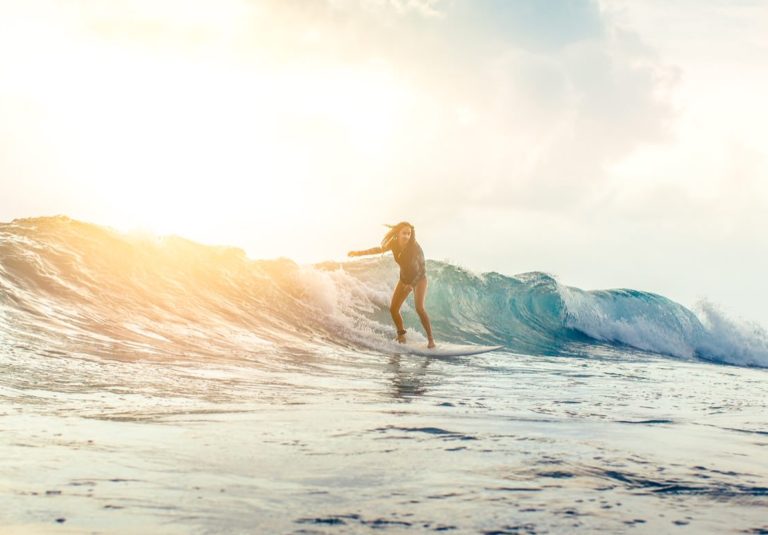 Surfer reitet eine kraftvolle Welle im offenen Meer bei Sonnenauf- oder -untergang mit goldenem Licht
