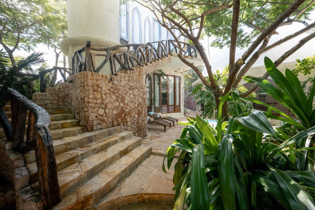 Außenbereich der Xanadu Villas mit steinerner Treppe, Holzgeländer, Terrasse und Pflanzen in Sansibar