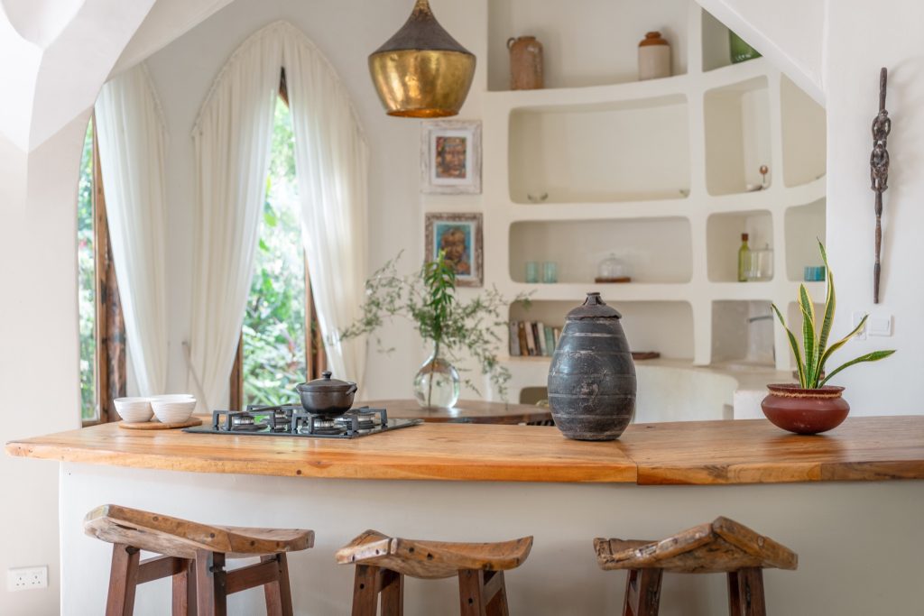 Küche der Villa Mbingu in den Xanadu Villas mit hölzerner Theke, Barhockern und großen Fenstern