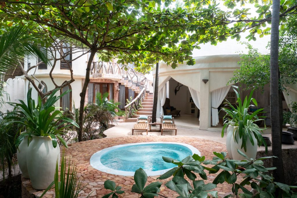 Innenhof der Xanadu Villas mit rundem Whirlpool, weißen Pflanzgefäßen und Treppe im Hintergrund