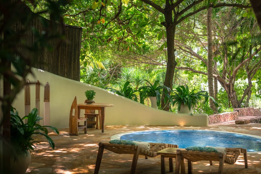 Ruhige Terrasse mit kleinem runden Pool, Holztisch, zwei Stühlen und grüner Vegetation in Sansibar