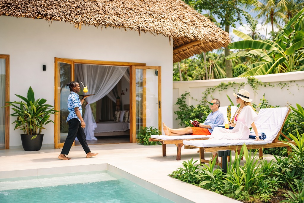 Außenbereich des Zanzi Resort mit Swimmingpool, Terrasse, weißen Wänden und Strohdach-Bungalows auf Sansibar