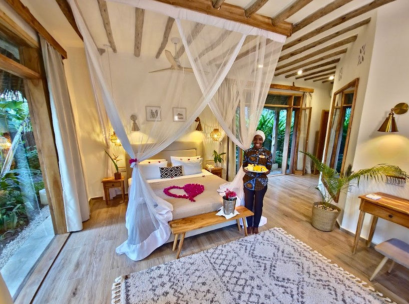 Hell eingerichtetes Zimmer im Zanzi Resort mit Moskitonetz, Holzmöbeln, Tageslicht und Terrasse in Sansibar