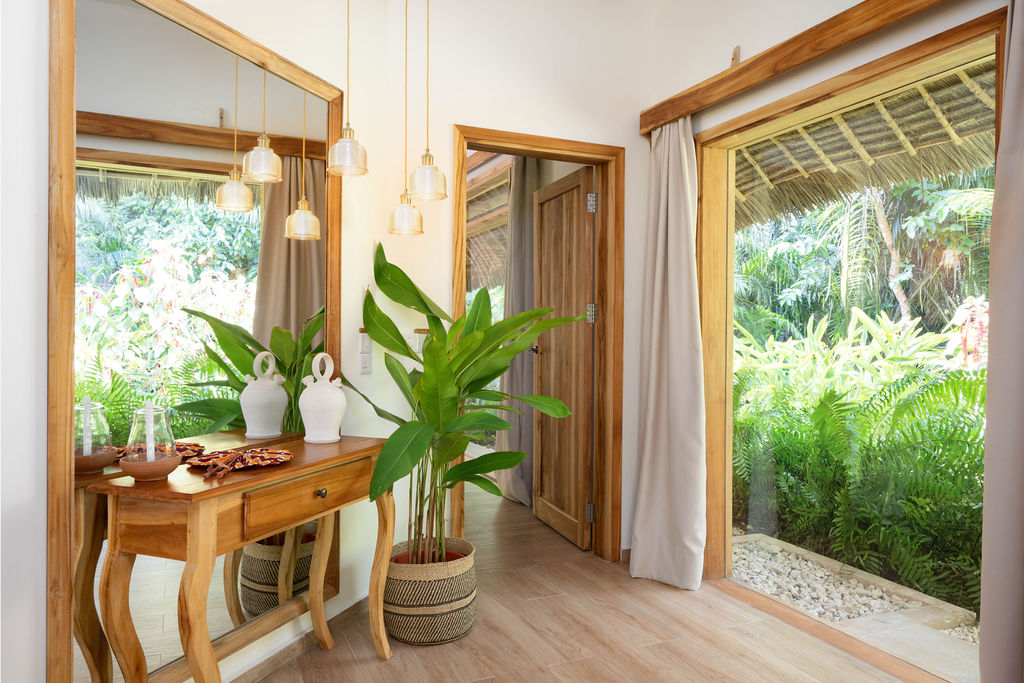 Flur in Zanzi Resort Luxury Garden Villa mit Holztisch, weißen Vasen, Pendelleuchten und Blick auf grüne Vegetation