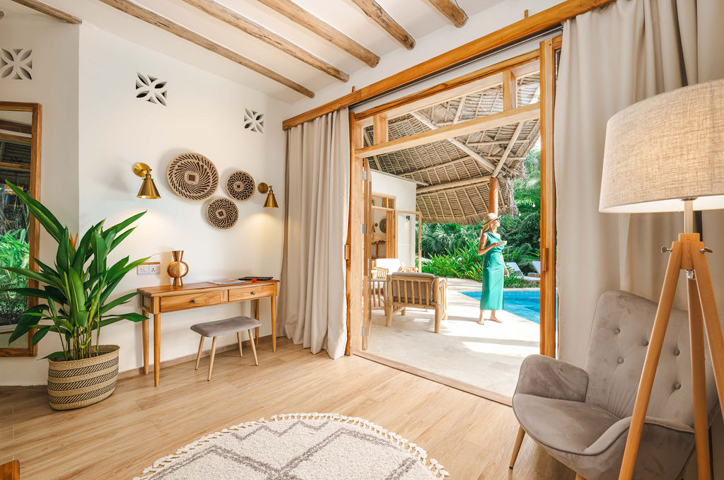 Hotelzimmer luxury garden villa mit Teppich, Holzkonsole, Polstersessel und Terrasse mit Poolblick im Zanzi Resort