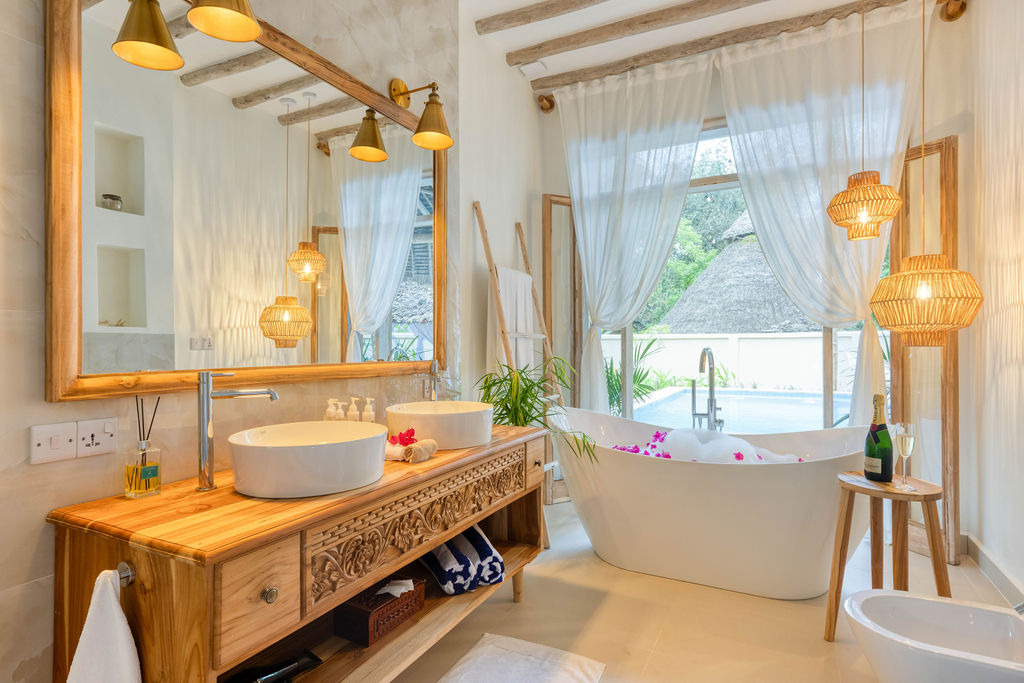 Badezimmer der Luxury Garden Villa im Zanzi Resort mit freistehender Badewanne, Holzwaschtisch und Fenster zur grünen.