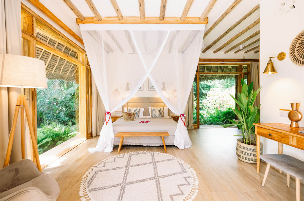 Zimmer der Zanzi Resort Luxury Garden Villa mit Baldachinbett, Holzmöbeln und großem Fenster zum Garten