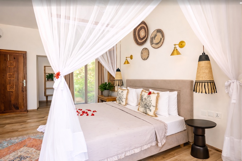 Zimmer der Oceanfront Villa im Zanzi Resort mit Himmelbett, weißen Vorhängen, Holzfußboden und dekorativen Körben an der Wand