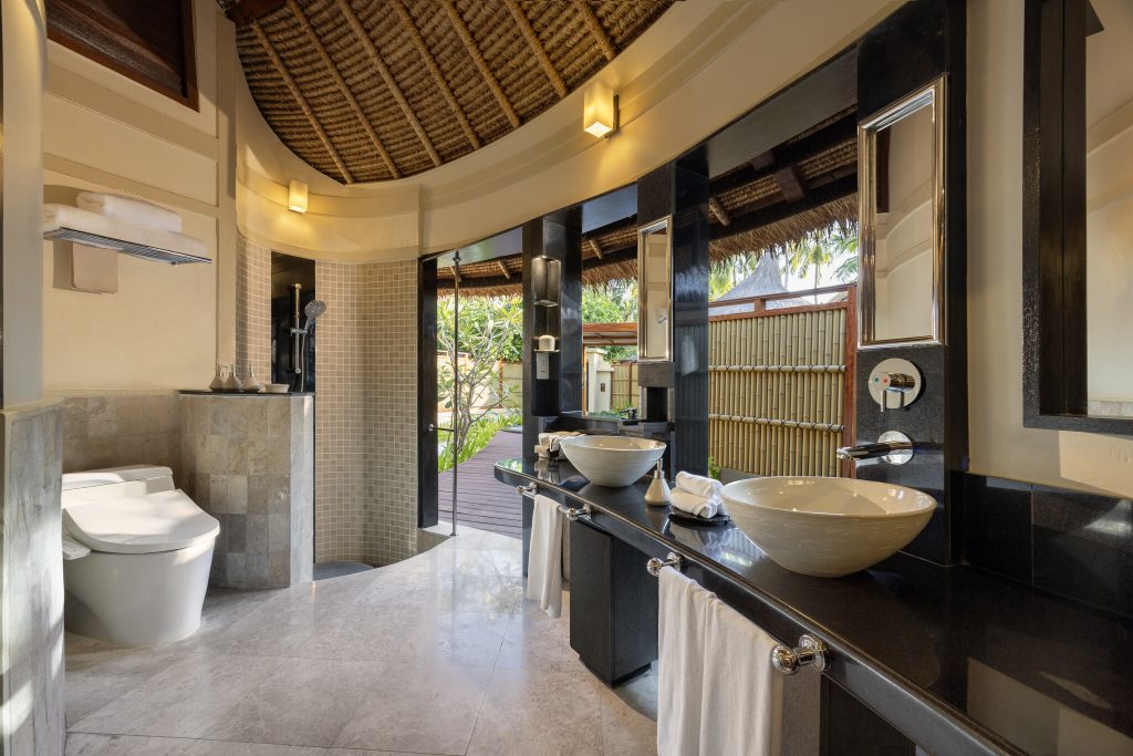 Badezimmer mit Doppelwaschbecken, Regendusche, WC, Steinboden, Holzdecke und Tageslicht im Banyan Tree Vabbinfaru