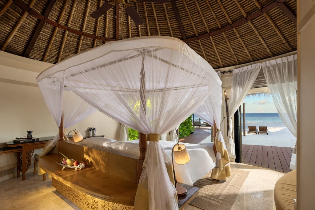 Zimmer der Grand Beachfront Pool Villa mit Himmelbett, Holzbalkendecke und Terrasse mit Meerblick