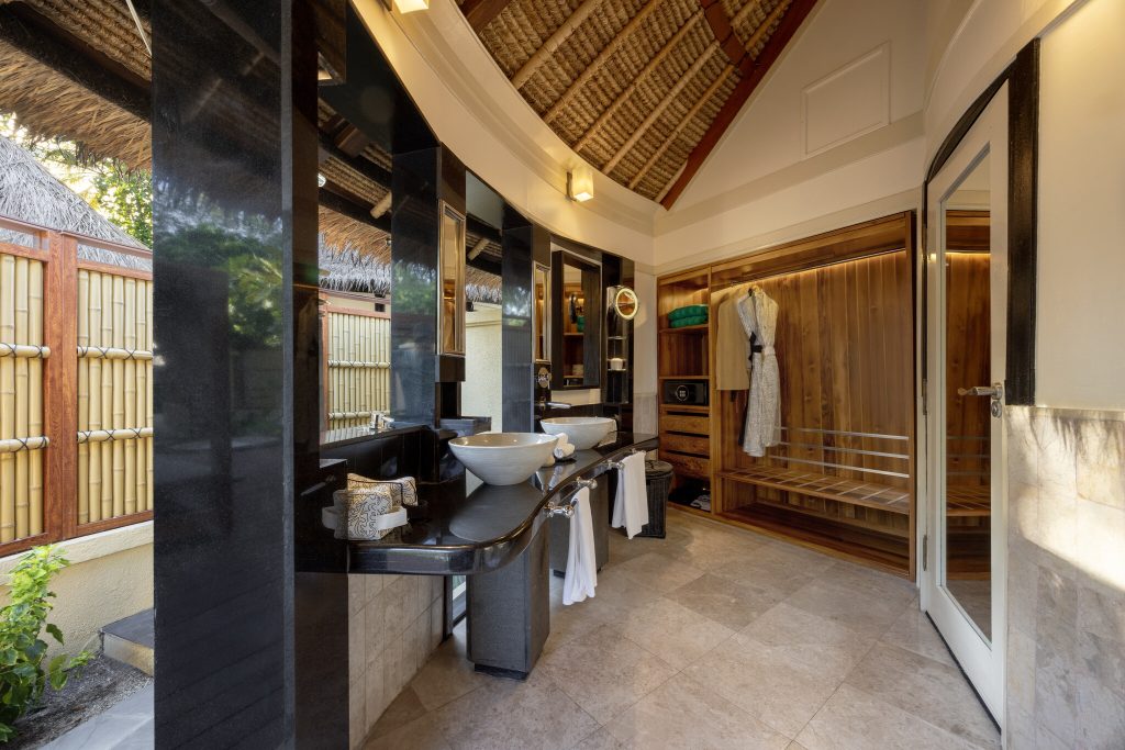 Badezimmer der Grand Beachfront Pool Villa mit Granitwaschtischen, Holz- und Rattanverkleidung, Tageslicht und Bambuszaun