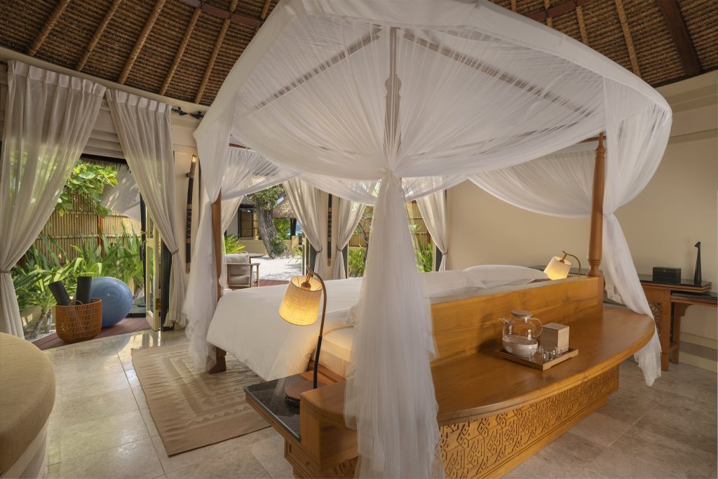 Zimmer der Wellbeing Sanctuary Pool Villa mit Himmelbett, Holzmöbeln und Blick auf Terrasse auf den
